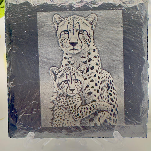 The Cheetah Cub Hugging Mother slate coaster by MokshaGoldSculptures, natural slate with etched cheetah design.