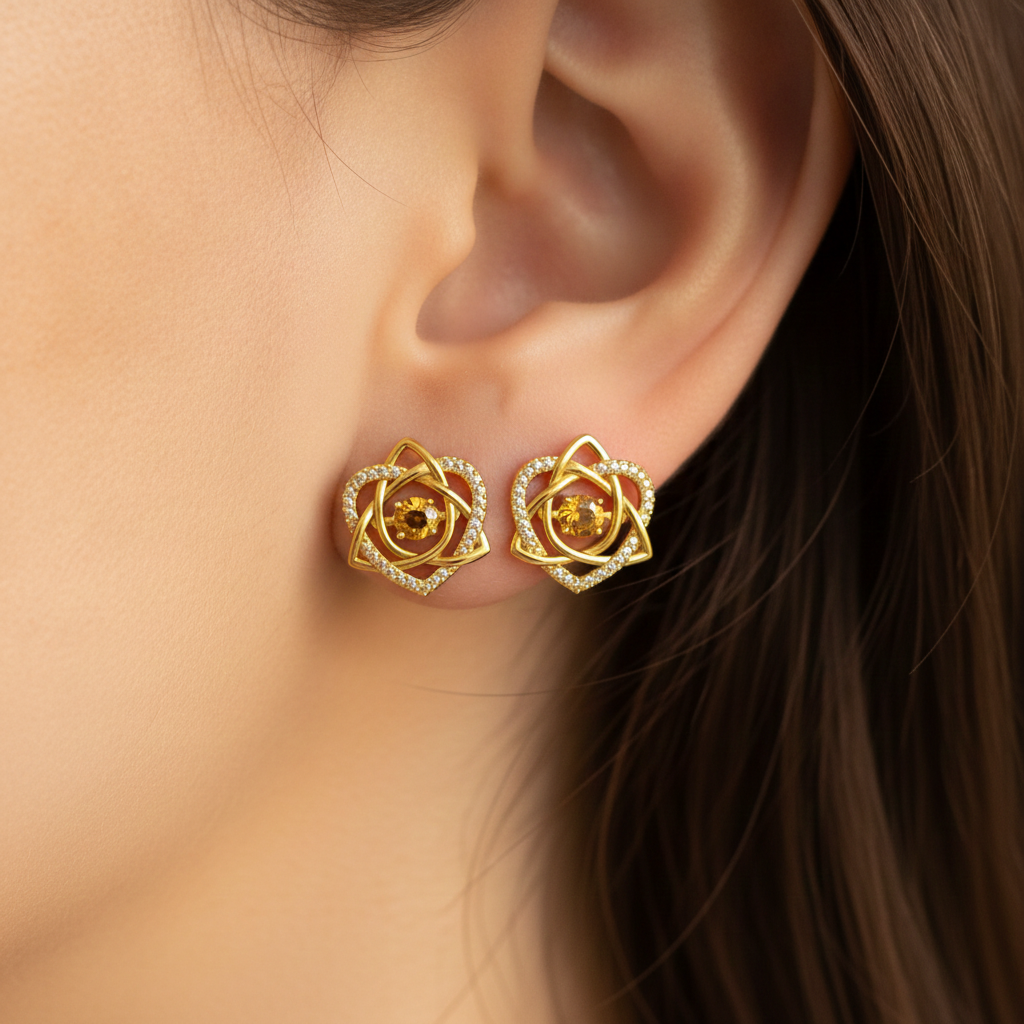 Celtic Trinity Knot Heart Stud Earrings in 9K gold by MokshaGoldSculptures on a woman’s ear, hair tucked back.