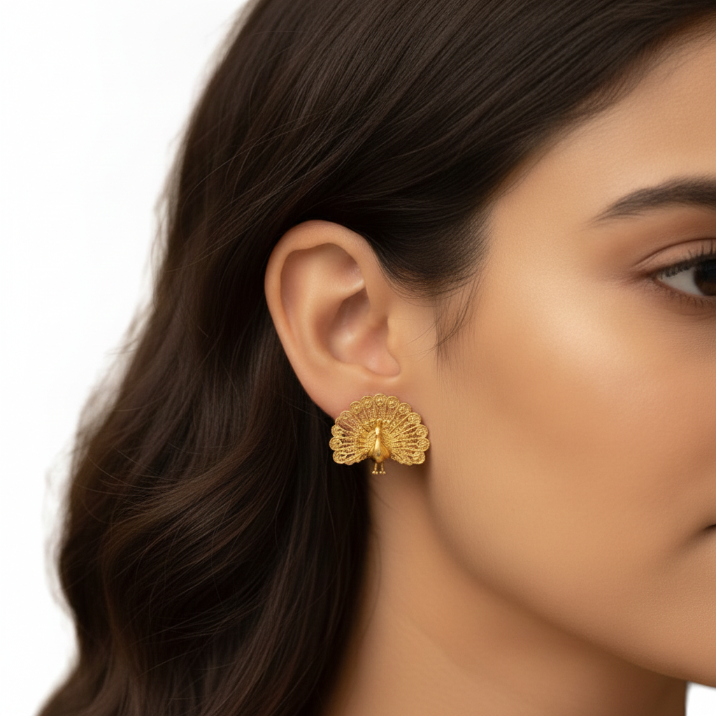 Peacock Stud Earrings in 9K gold by MokshaGoldSculptures, worn by woman with wavy dark hair, close-up.