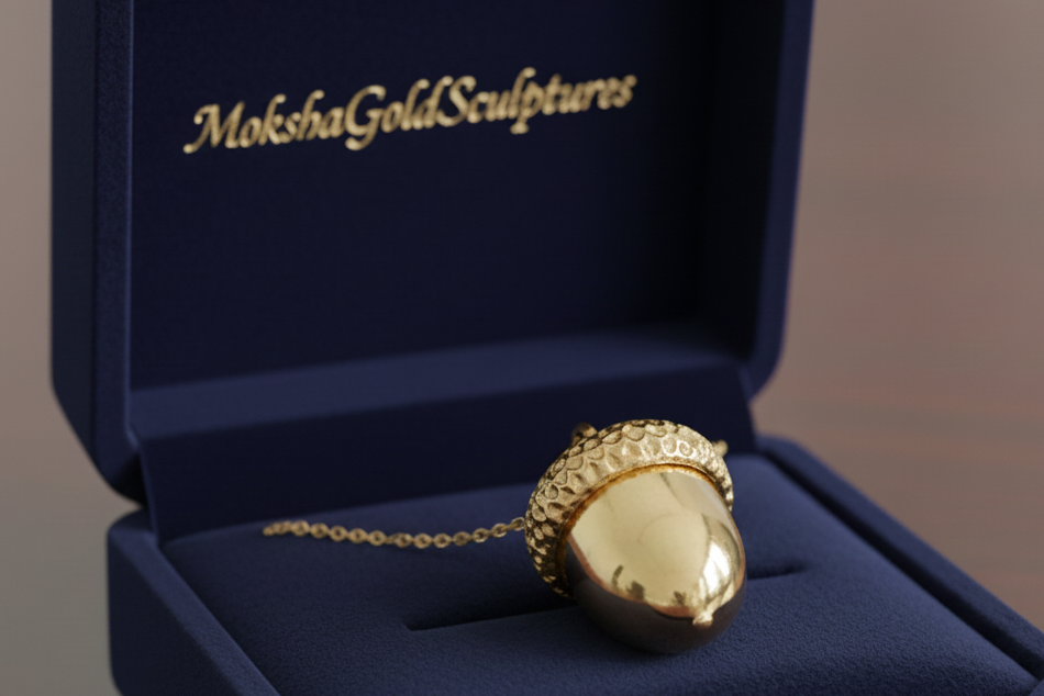The Gold Acorn Pendant Necklace in 24K gold plate by MokshaGoldSculptures, shown in a blue branded box.