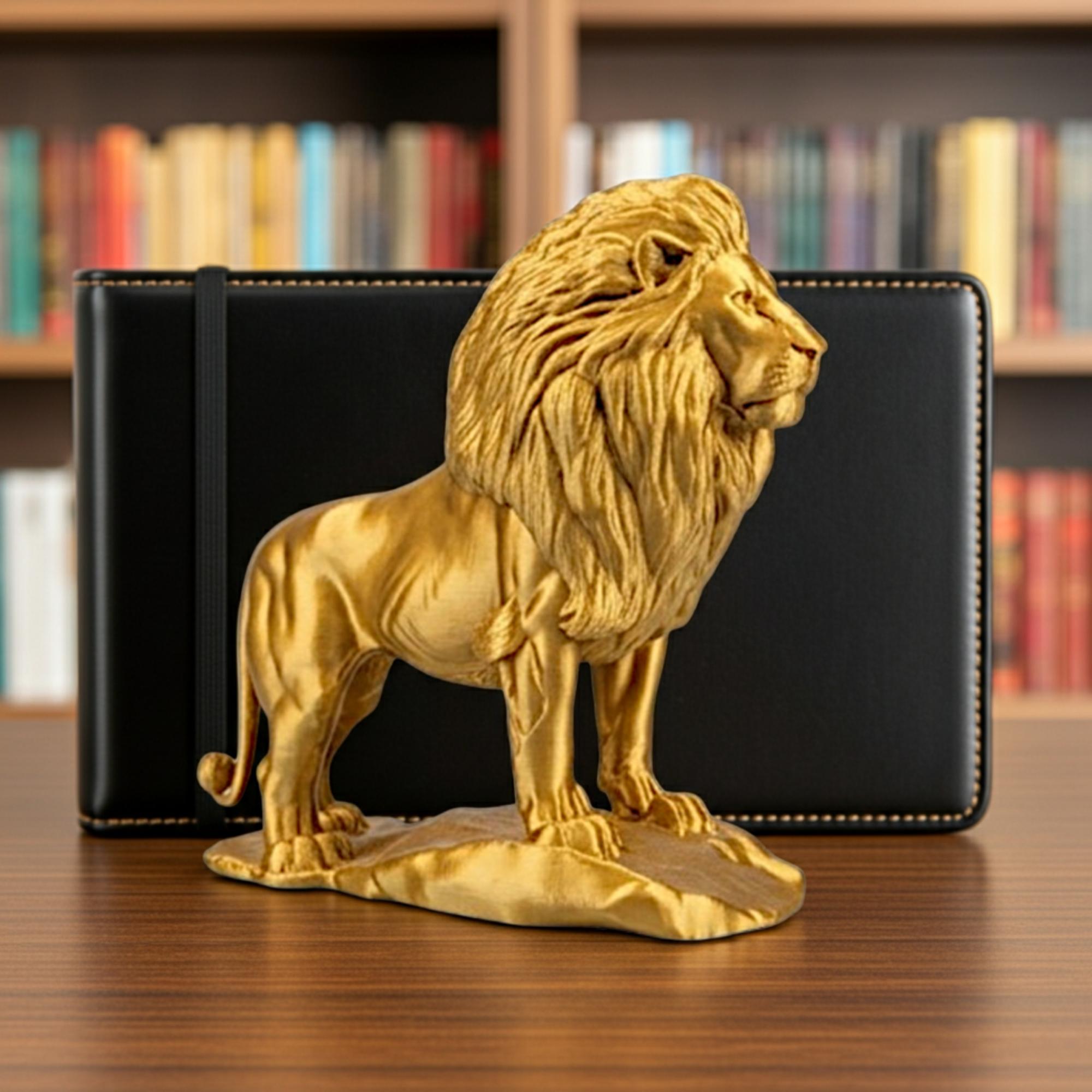 Gold Lion on Rock statue in metallic PLA finish by MokshaGoldSculptures, displayed on wood table, books blurred behind.